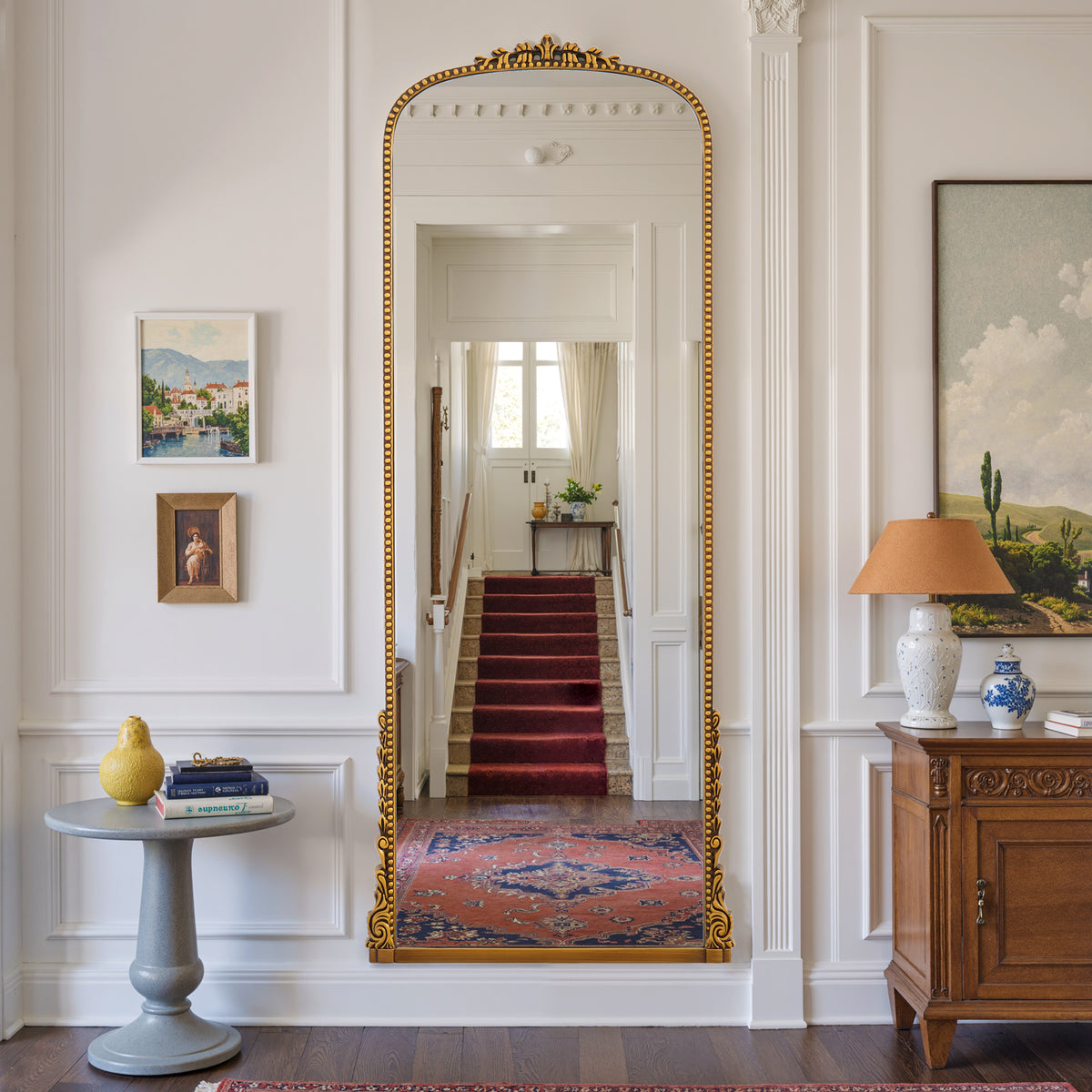 Aurelia antique gold ornate arched mirror mounted in a hallway
