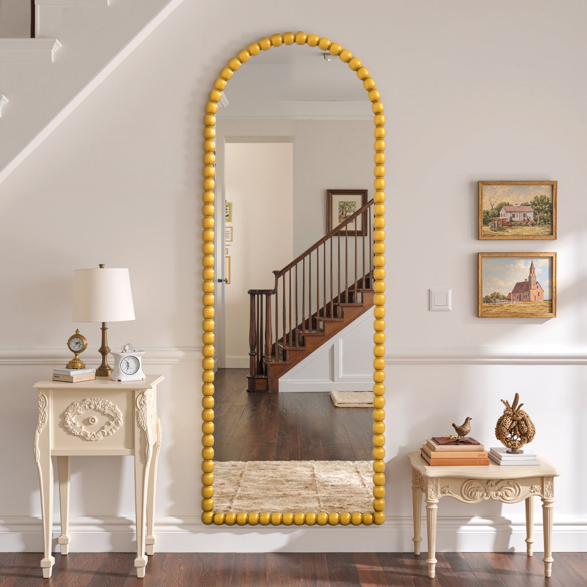 Delphine antique gold beaded arched mirror mounted in a hallway