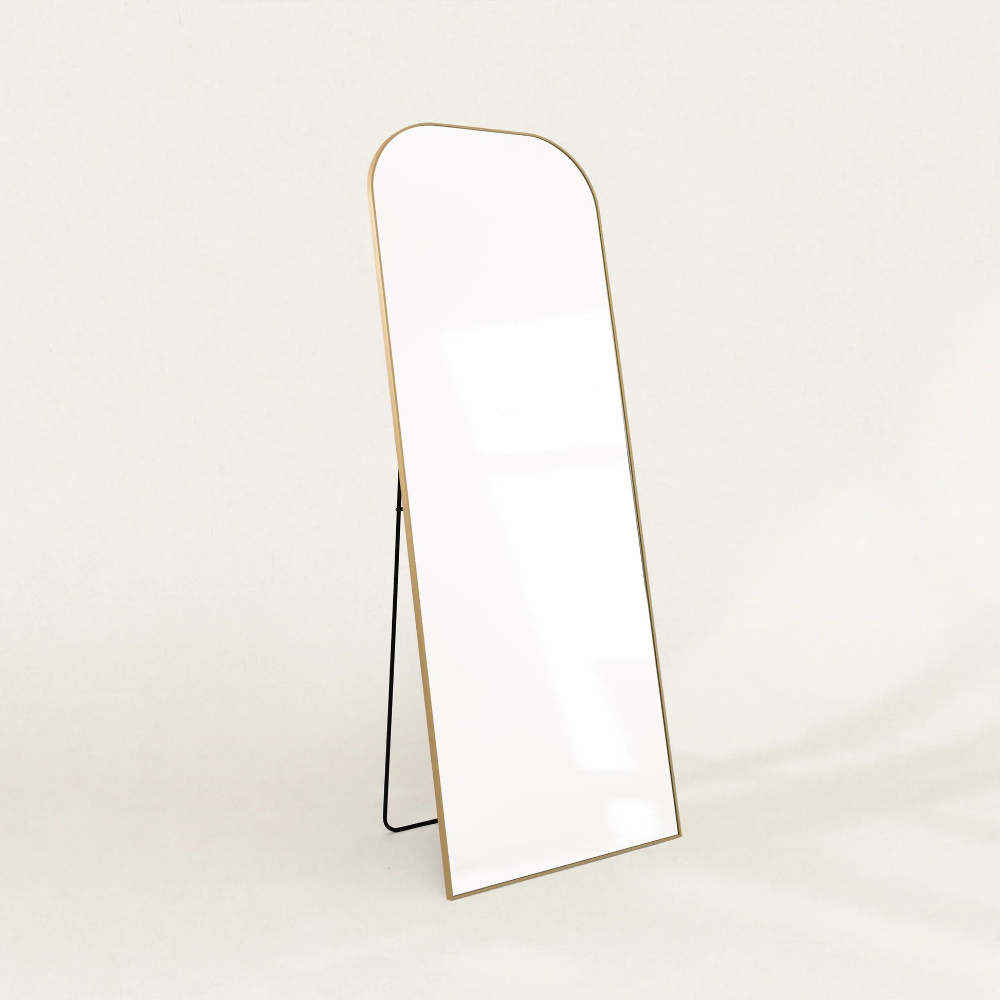 Elliot gold curved full-length mirror on its folding stand