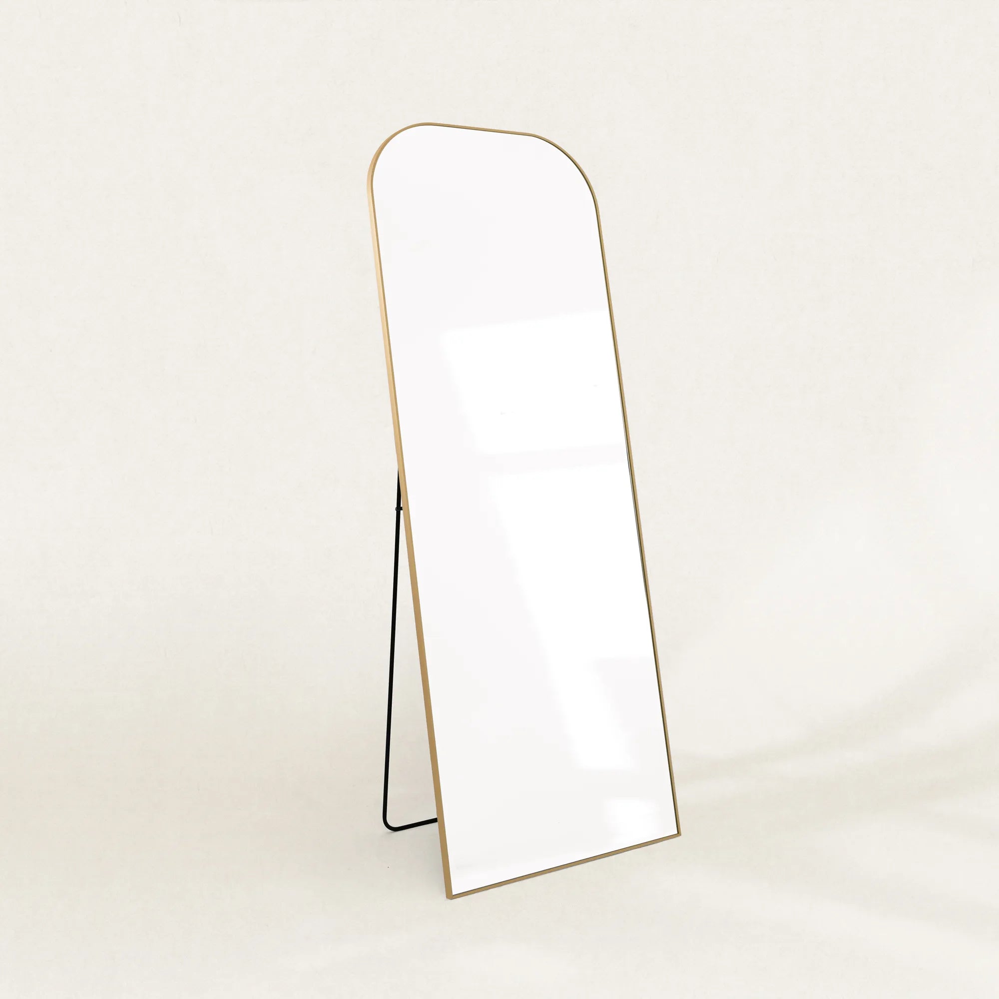 Elliot gold curved full-length mirror on its folding stand