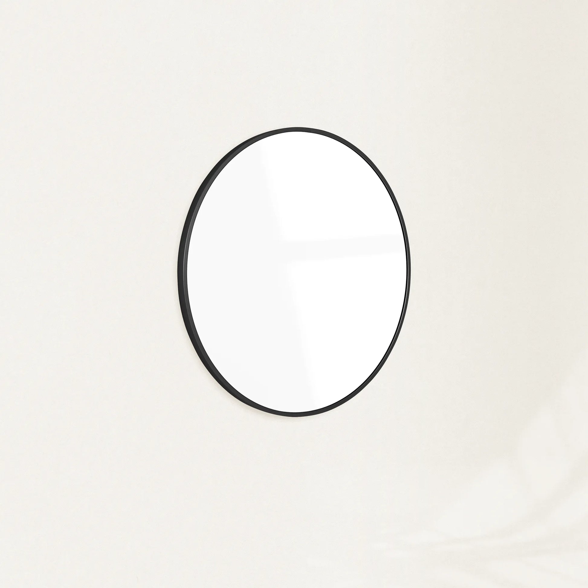 Sylvie round wall mirror with a slim black frame mounted on a plain wall