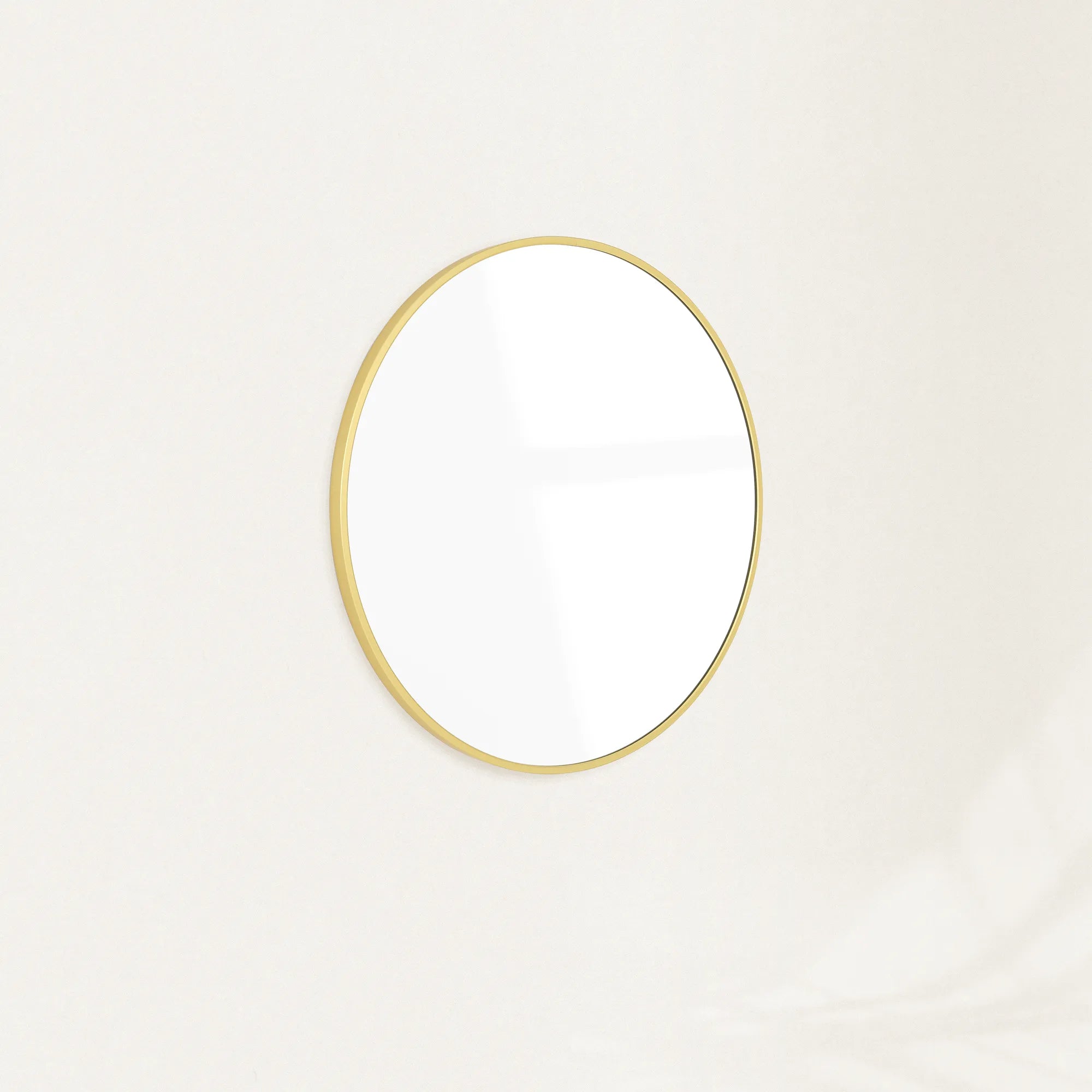 Sylvie round wall mirror with a slim gold frame mounted on a plain wall