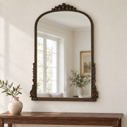 Evelyn antique bronze ornate wall mirror above a wooden console in a vintage-inspired interior
