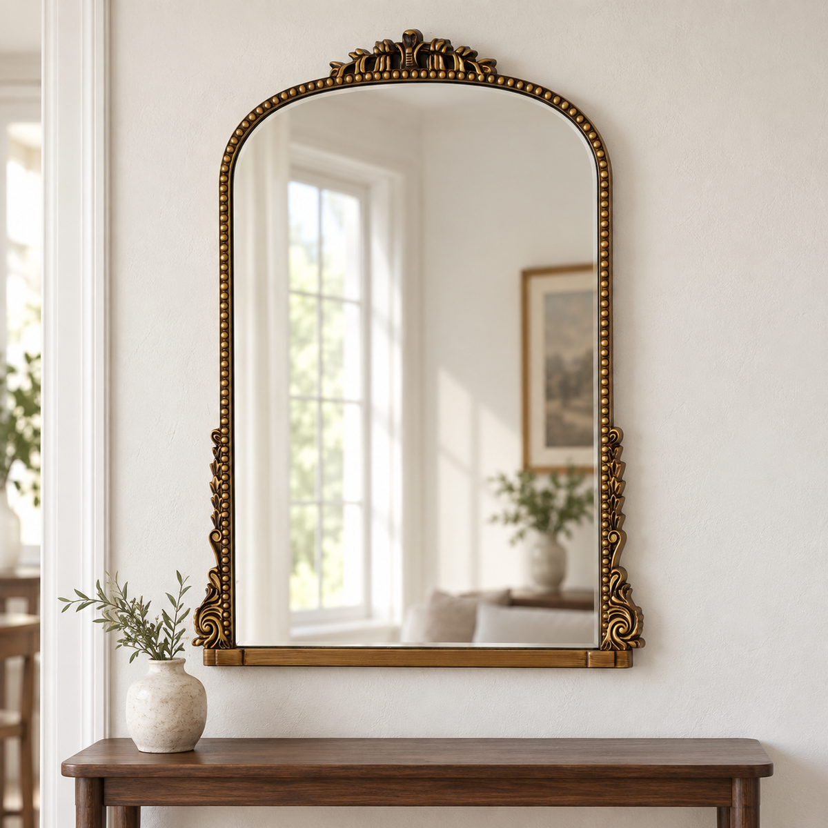 Evelyn antique gold ornate wall mirror above a wooden console in a vintage-inspired interior