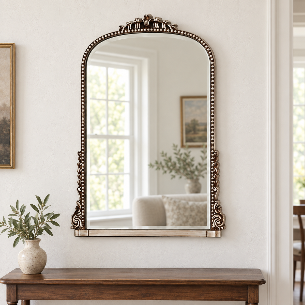 Evelyn antique silver ornate wall mirror above a wooden console in a vintage-inspired interior